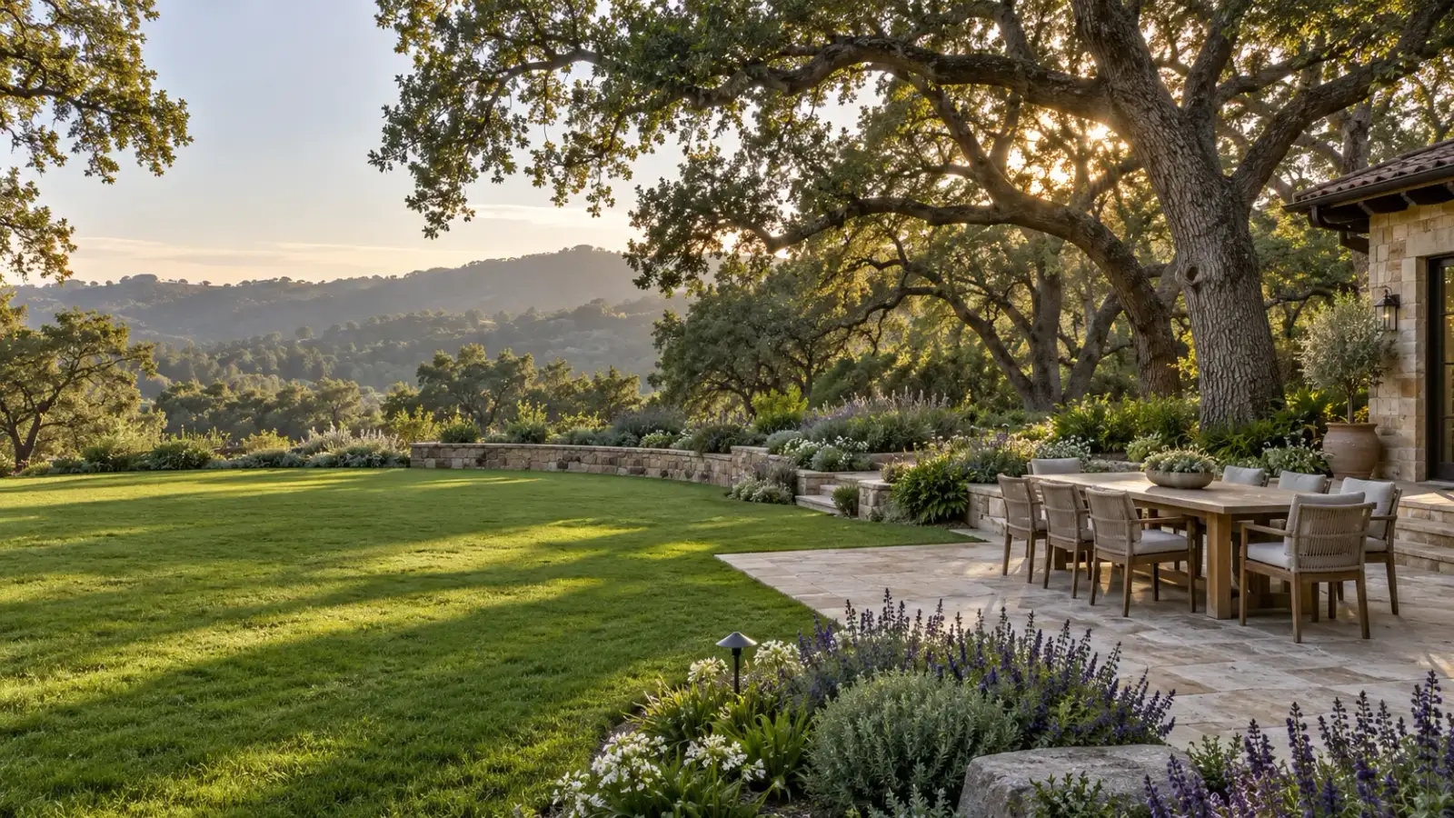 Stone seat wall, lawn and travertine patio under oaks in Monte Sereno