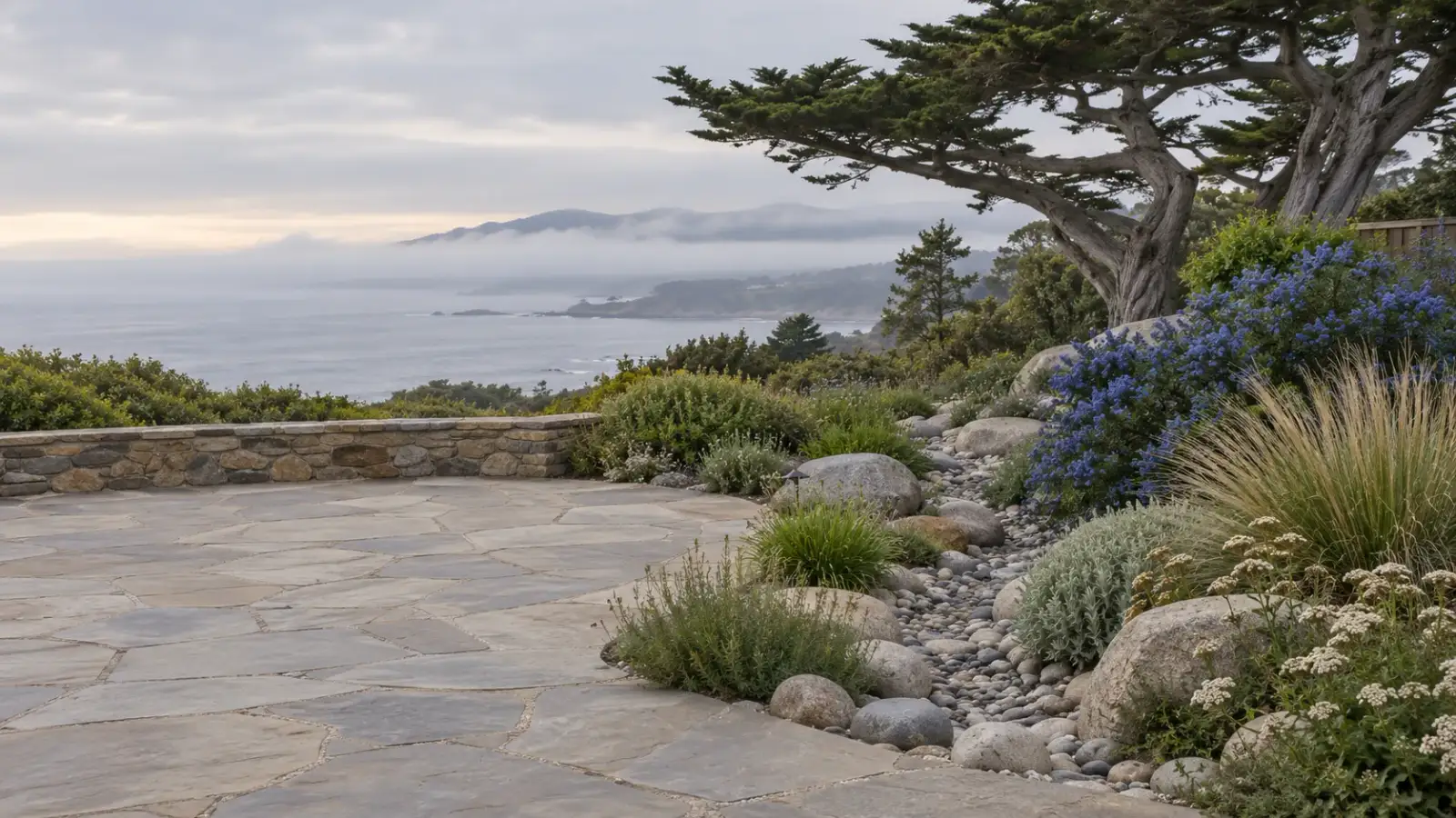 Flagstone patio and dry creek bed with coastal plants above Monterey Bay