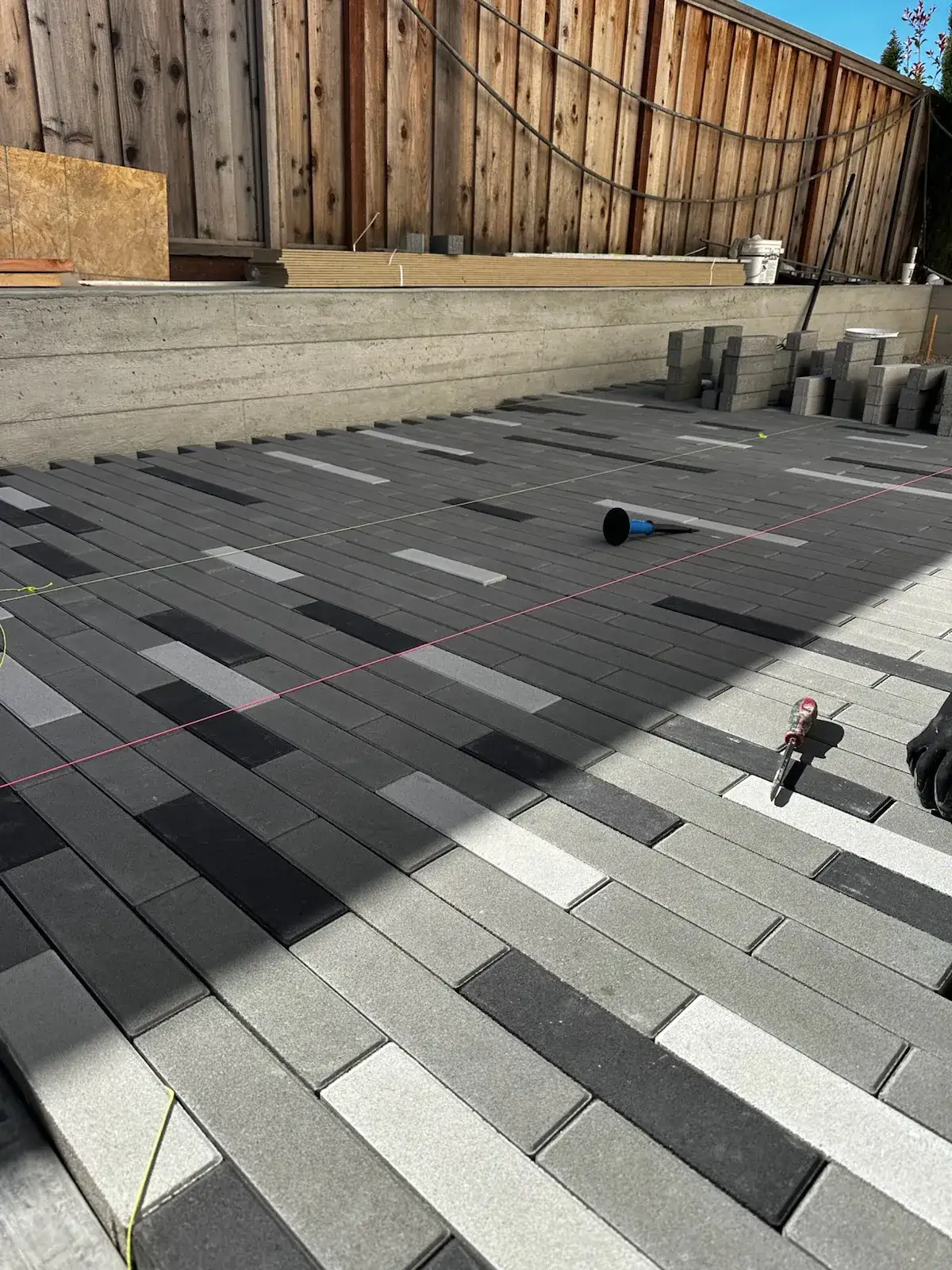 Linear paver patio being laid in charcoal, grey and white tones
