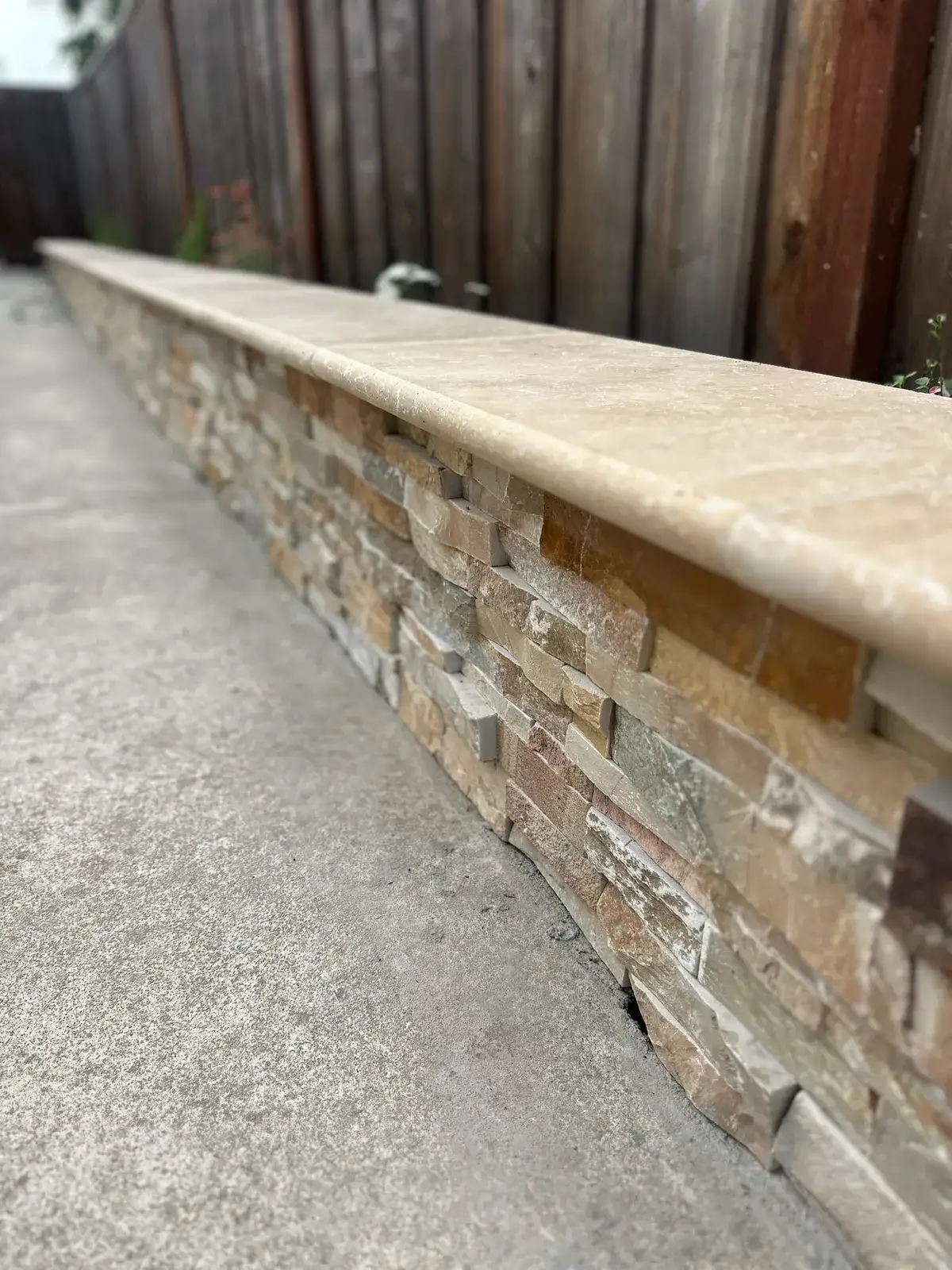 Travertine caps a seat wall faced in stacked stone.