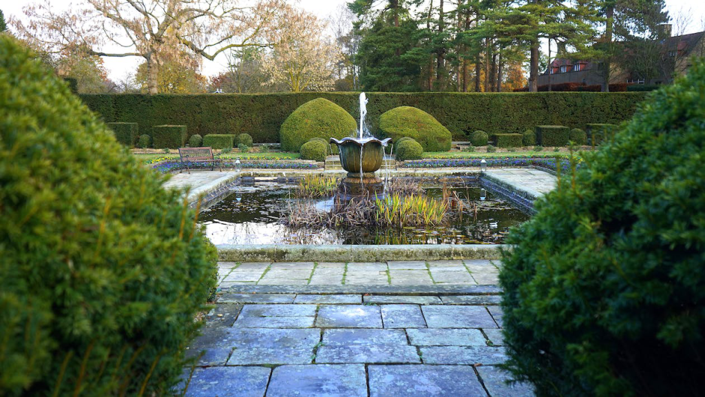 Water fountain amidst lush green trees.