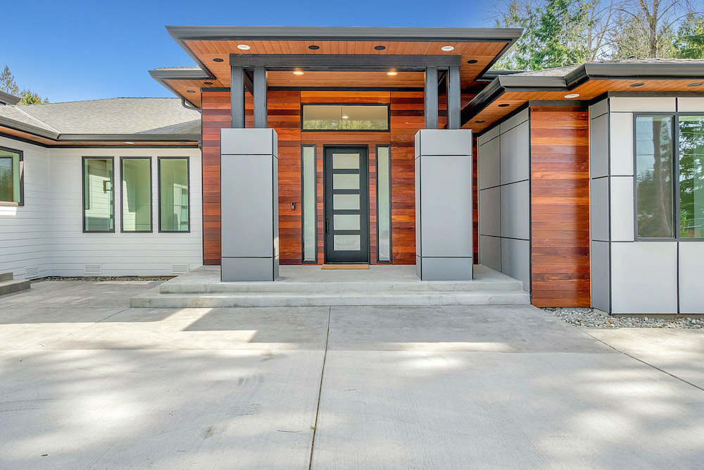 Modern house with a concrete driveway and wood accents, exemplifying the use of concrete in contemporary residential design.