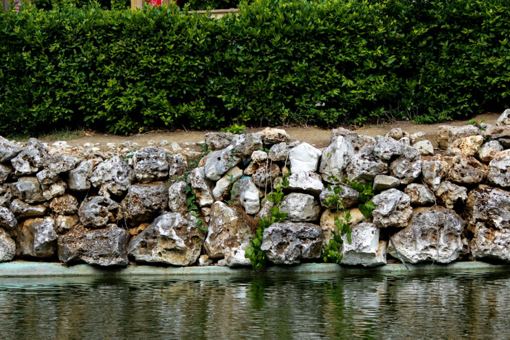 A retaining wall made of stones against a pond.