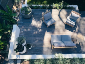A retaining wall surrounding a deck with chairs and plants.