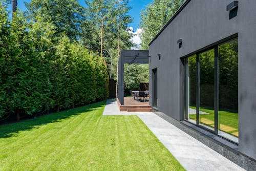Exterior of a modern house with a fresh landscape makeover, including lawn installation, sodding, and creative hardscape features.
